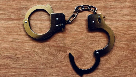 handcuffs-on-wooden-background-P6TYVYA-scaled