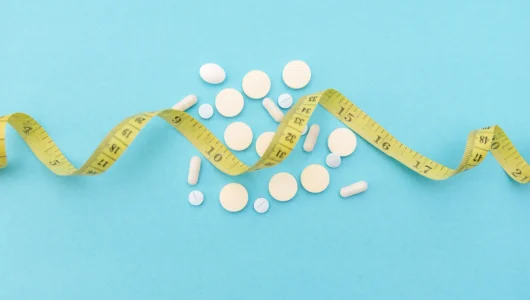 weight-loss-pills-and-measuring-yellow-tape-on-blu-2026-03-24-12-34-45-utc